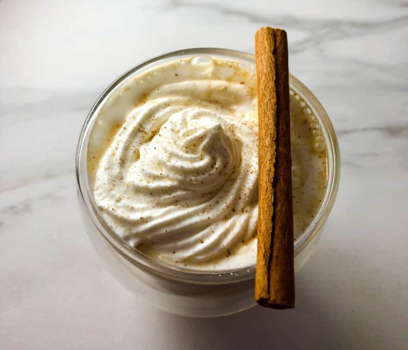 top view of boozy apple cider with whipped cream and nutmeg