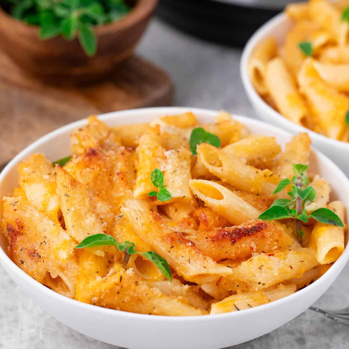 instant pot mac and cheese in a bowl with herbs on top.
