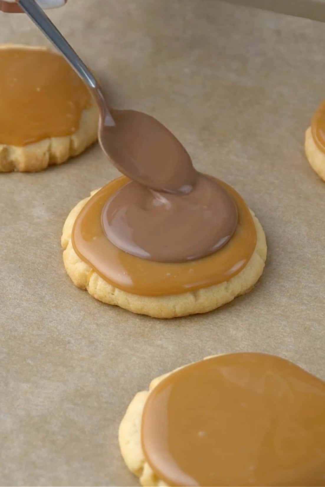 melted chocolate being placed on caramel for twic cookies.