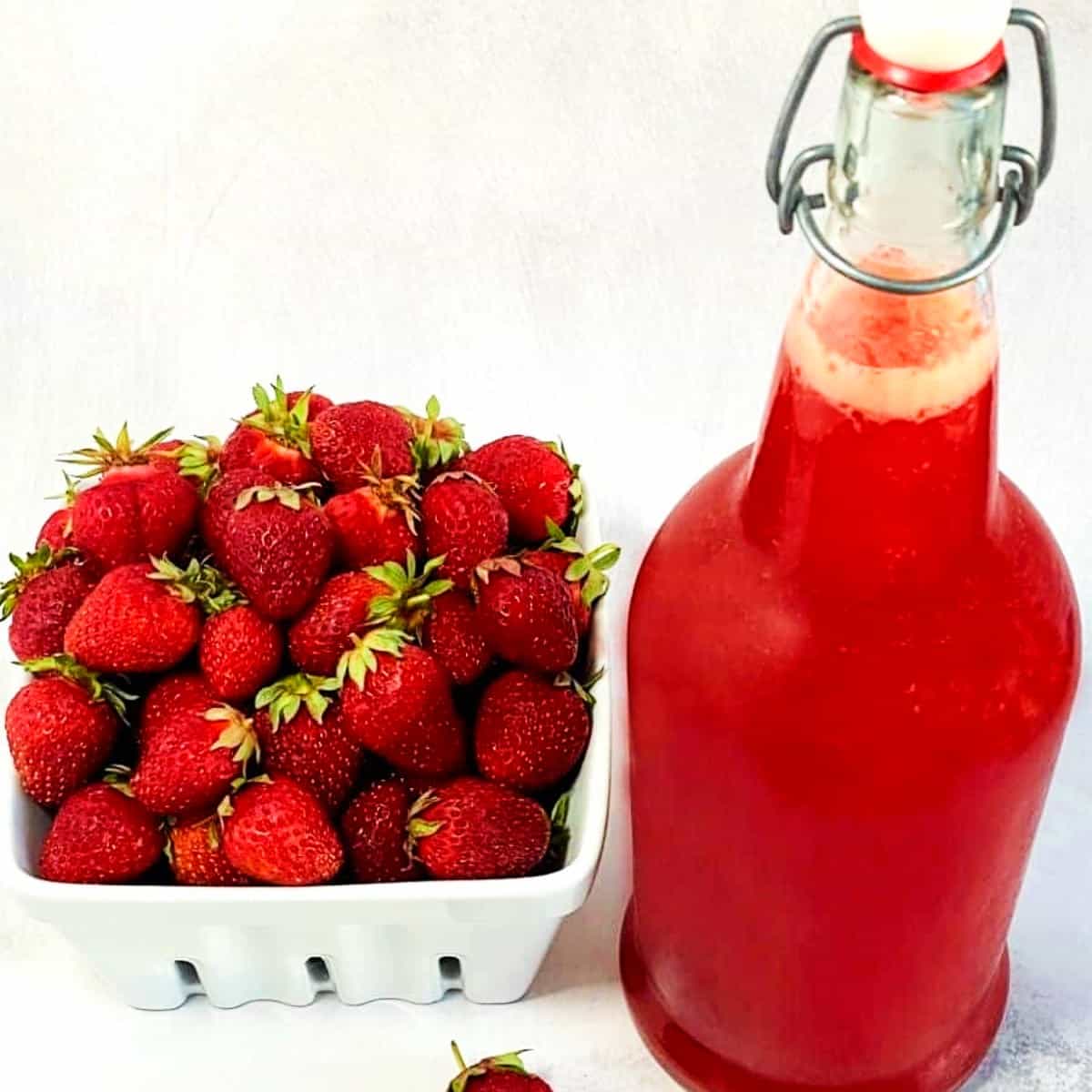 strawberry shrub in a bottle and fresh strawberries.
