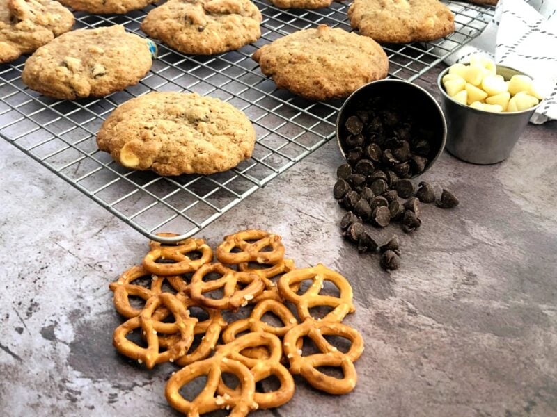 kitchen sink cookies on a cooling rack with pretzels and dark and white chocolate chips.