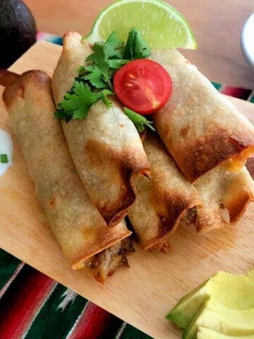 air fryer taquitos with garnishes.