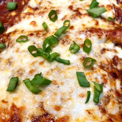 enchiladas with cheese and green onions on top