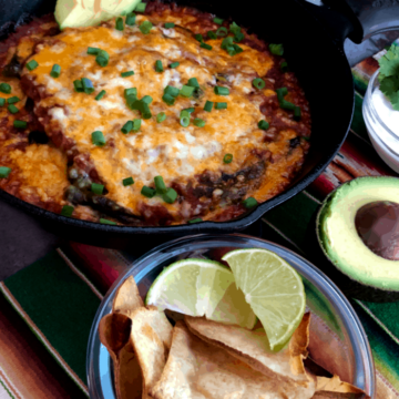 baked chile rellenos in a cast iron pan with chips, sour cream and avocado