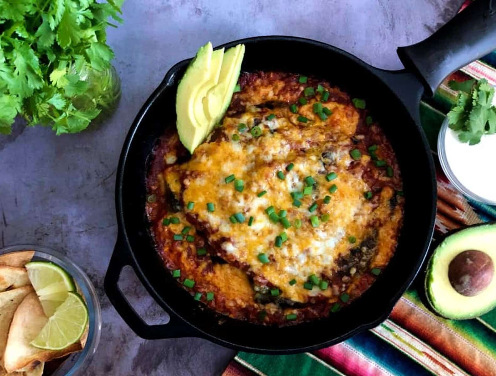 baked chile rellenos in a pan with green onions on top.