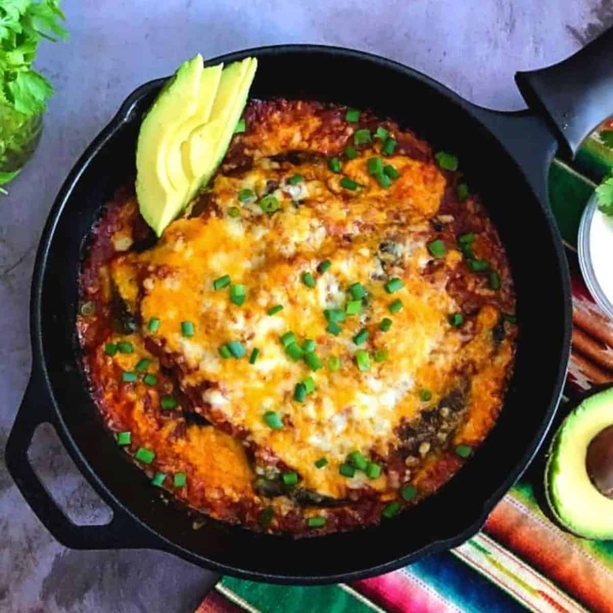 baked chile rellenos with green onion and avocado garnishes.