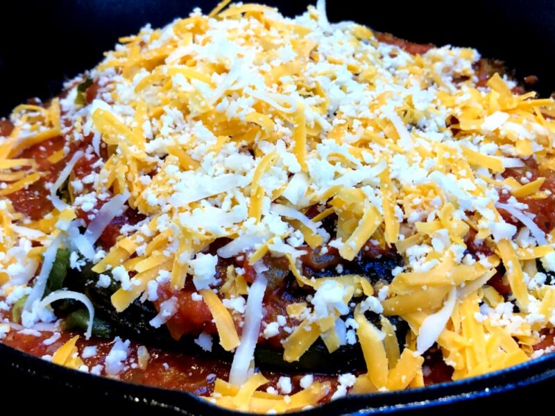 roasted-poblano-peppers-stuffed-with-cheese-in-a-pan-covered-with-cheese-and-salsa