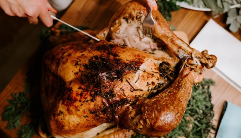 roasted turkey with herbs  being carved on a cutting board.