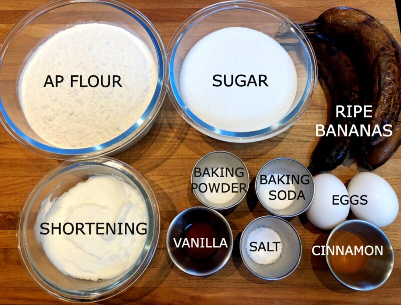 Banana cake ingredients: flour, sugar, bananas, shortening, vanilla, salt, baking powder and soda, cinnamon and eggs