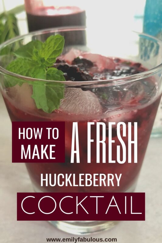 a huckleberry cocktail in a lowball glass with a fresh mint sprig