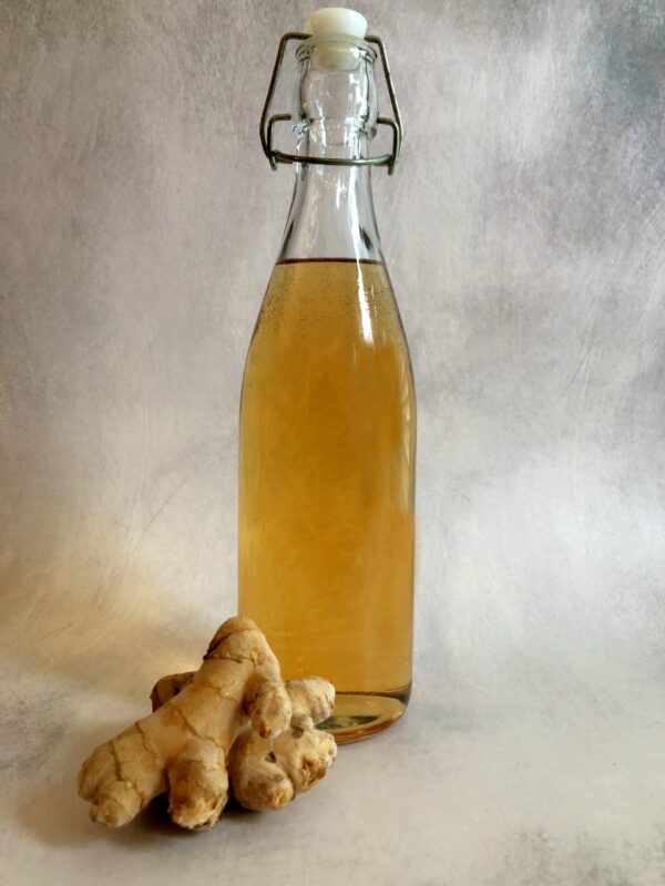 a flip top bottle of ginger syrup with fresh ginger in front