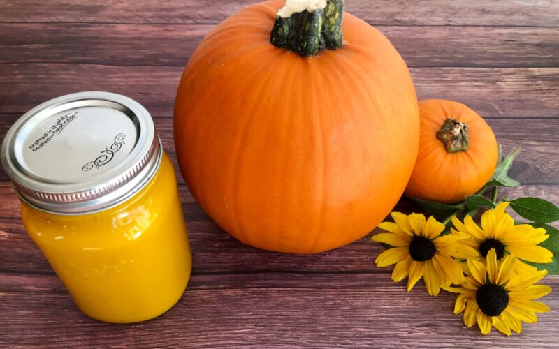 homemade pumpkin puree in a jar with sugar pumpkins and fall flowers