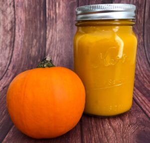 pumpkin puree in a jar next to a pumpkin