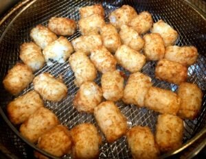tater tots in air fryer basket after cooking