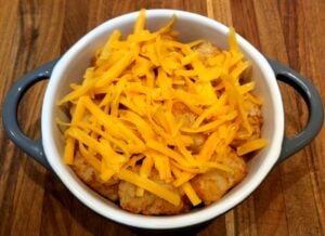 tater tots in oven-safe dish with second layer of tots and cheese
