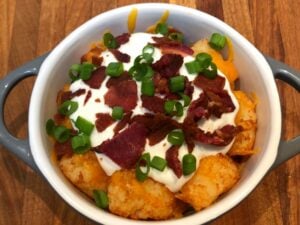 tater tots with melted cheese, sour cream, bacon and green onions