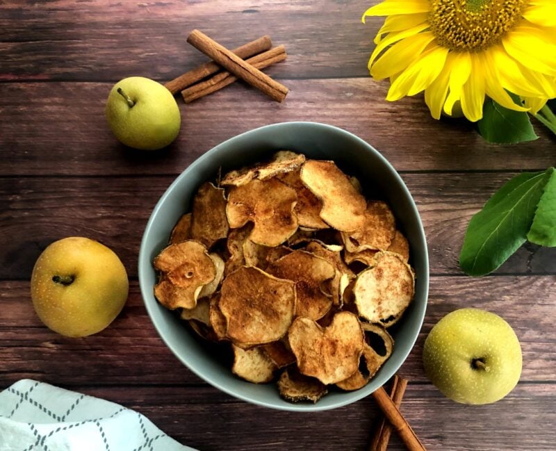 asian pear chips in a bowl and fresh pears and cinnamon sticks