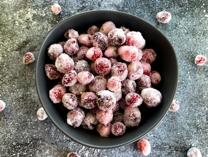 boozy candied cranberries in a bowl with sugar