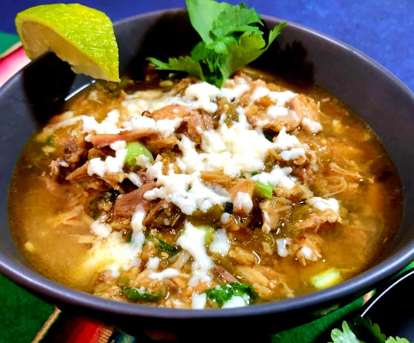 a bowl of green chile chicken soup with melted cheese