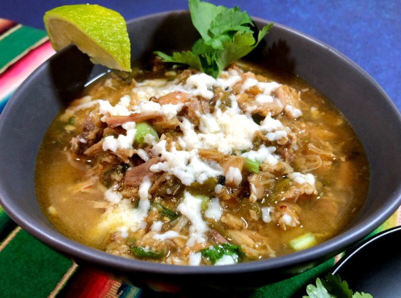 bowl of chicken chile verde made in the instant pot with melted queso fresco on top
