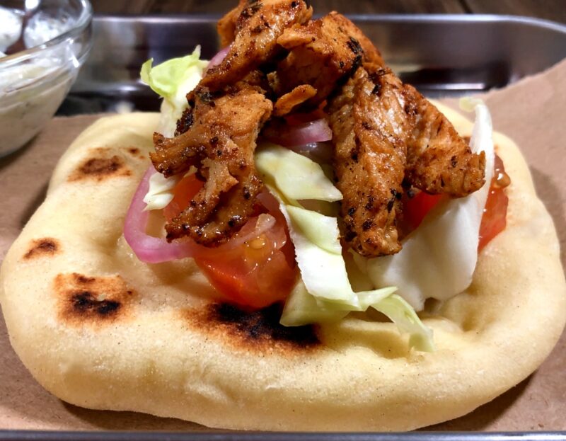 chicken gyro open on a tray with tomato, onion and lettuce