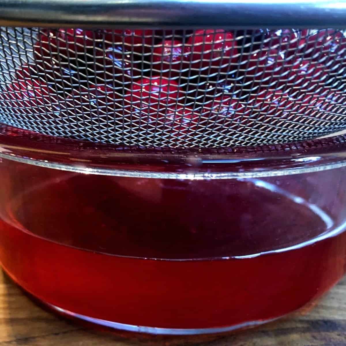 cranberries being strained from syrup.