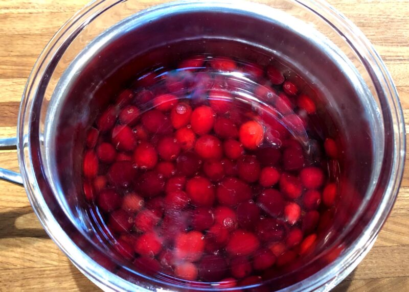 cranberries in syrup with a bowl on top to submerge