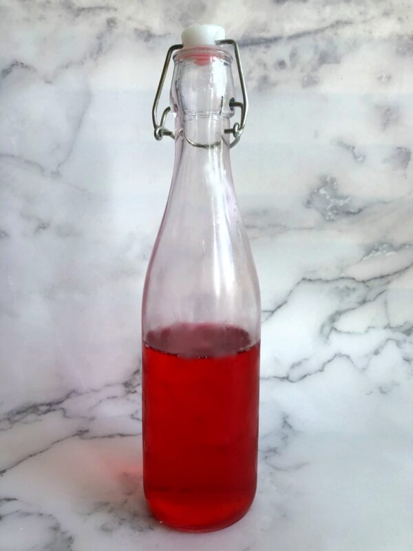 cranberry orange liqueur syrup in a flip-top bottle