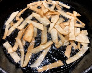 tortilla strips frying in oil