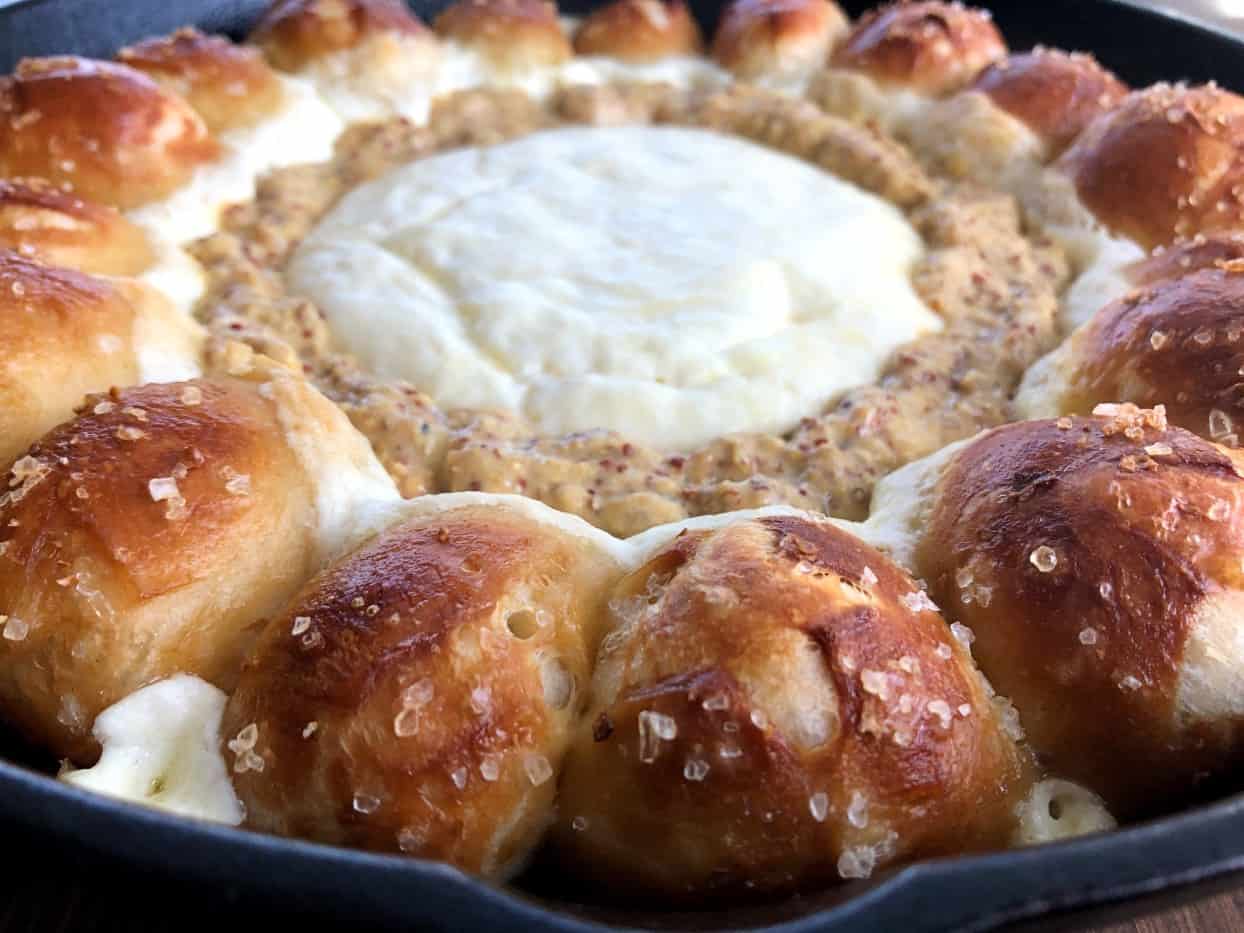 pretzels around cheese dip in a skillet.