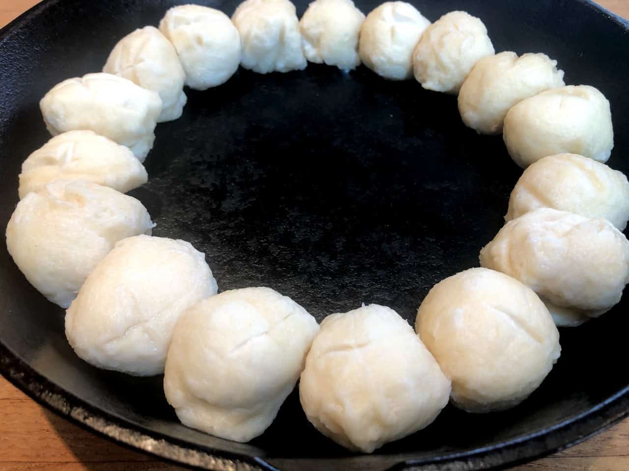 raw pretzel rolls in cast-iron skillet.