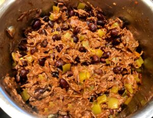 shredded beef with mexican spices, green chiles and black beans in a pan