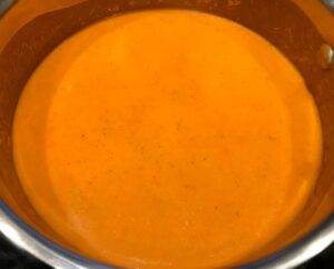 tomato orange soup in a pan with cream added