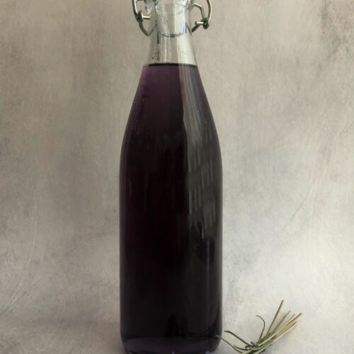 lavender syrup in a bottle with a sprig of dried lavender