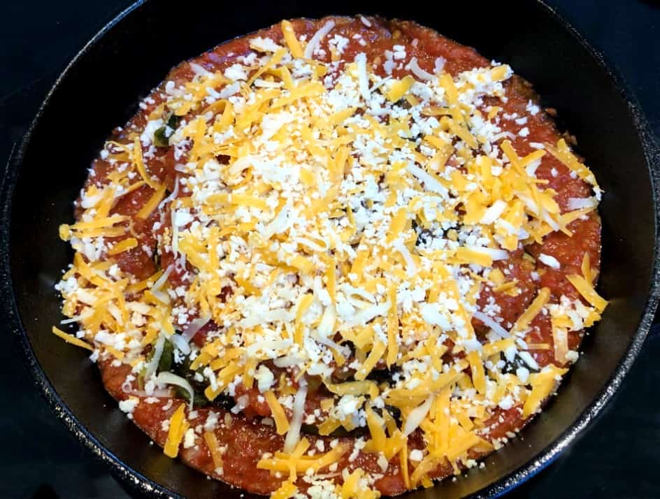 roasted poblano peppers stuffed with cheese in a pan with salsa.