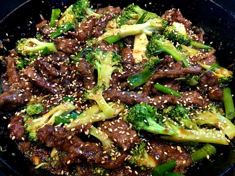 sticky beef and broccoli in a cast iron pan