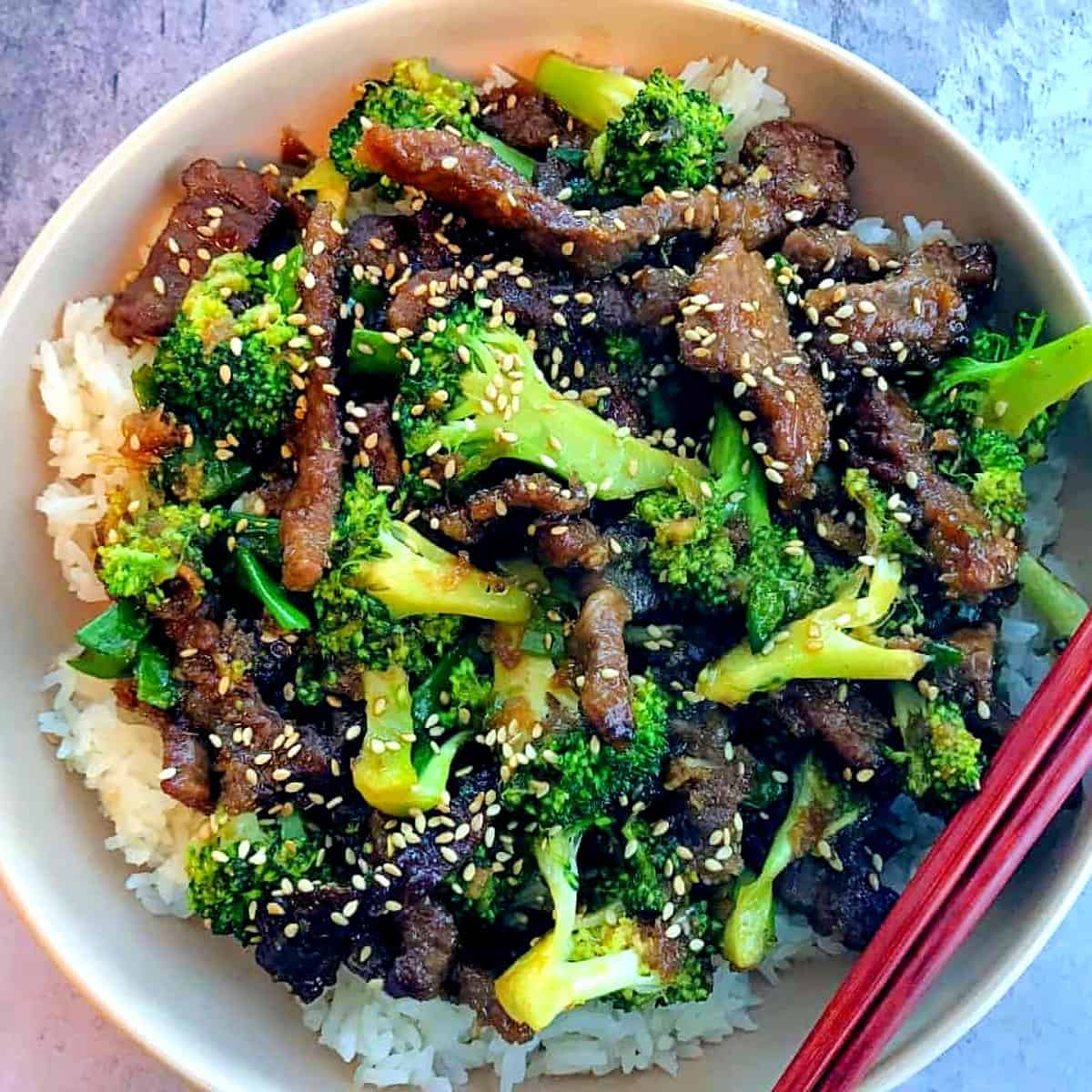 sticky-beef-broccoli-and-rice-in-a-bowl-with-chopsticks-and-sesame-seeds