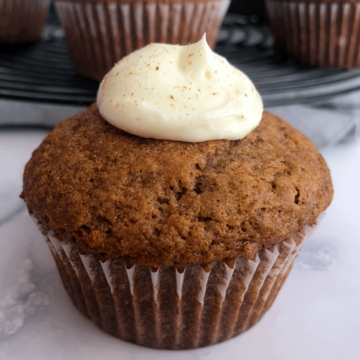 banana muffin with cream cheese frosting and ground cinnamon