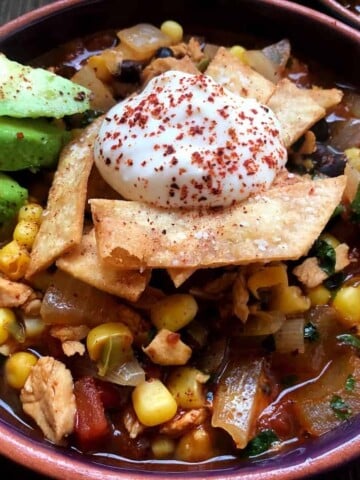bowl of tortilla soup with avocado and sour cream.