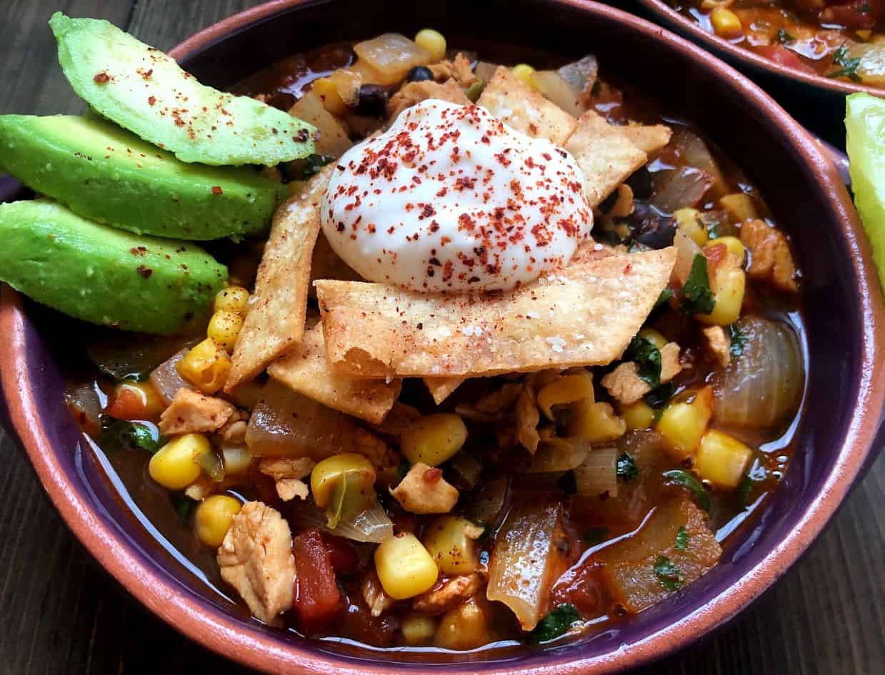 bowl of tortilla soup with avocado and sour cream.