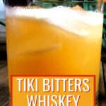 tiki bitters whiskey sour with a cherry and orange garnish