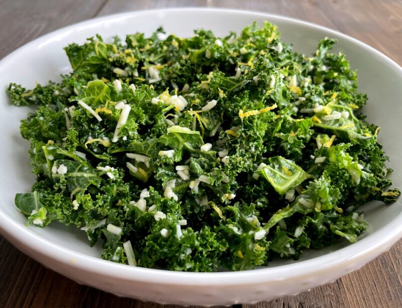 kale salad in a bowl with parmesan cheese and lemon zest on top