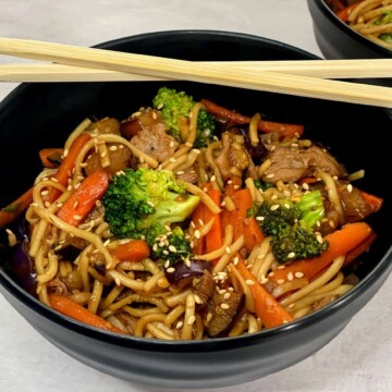 a bowl of udon noodles with beef and vegetables