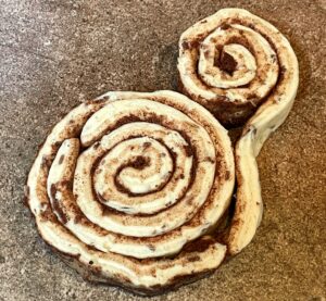 canned cinnamon rolls being rolled together