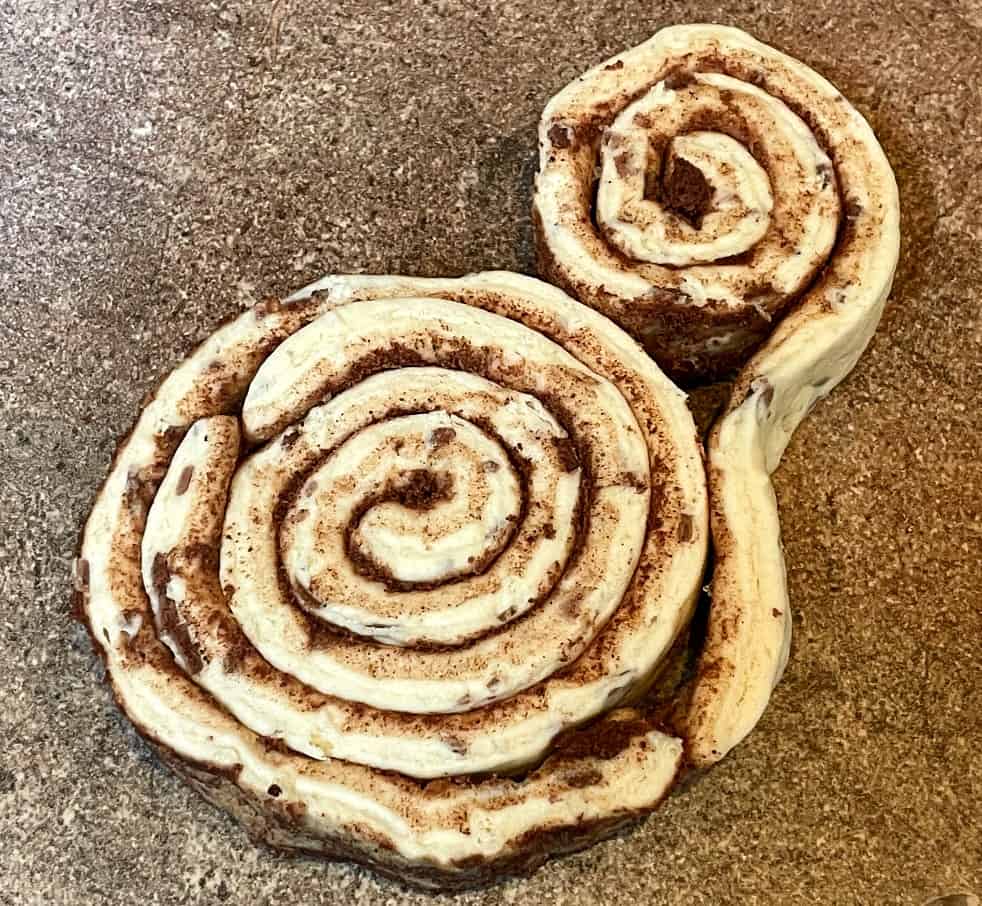 canned cinnamon rolls being rolled together.
