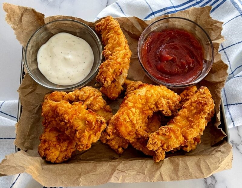 chicken strips on a tray with ranch and ketchup