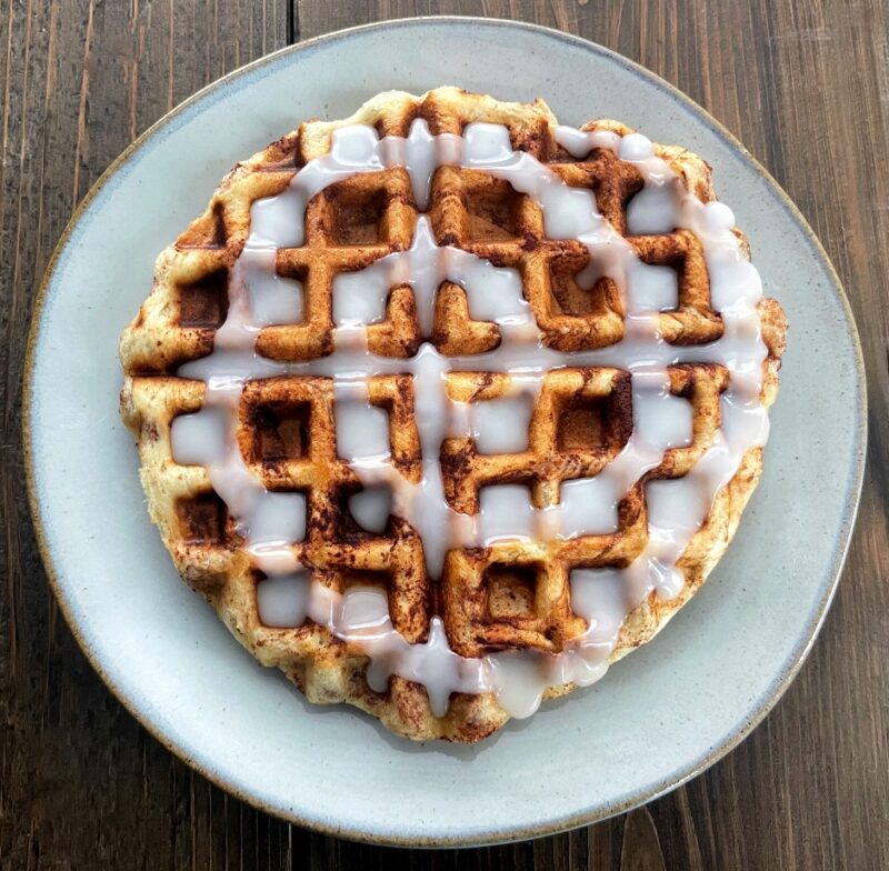 cinnamon roll waffle on a plate with icing on top