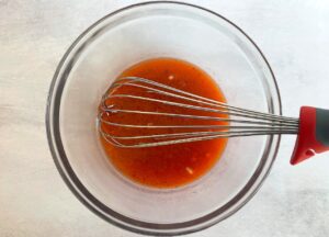 strawberry shrub salad dressing in a bowl with a whisk