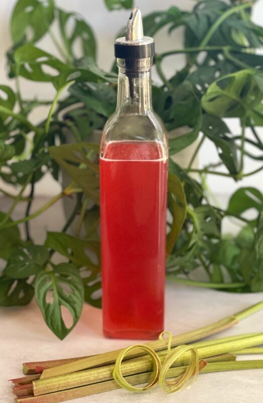rhubarb syrup in a bottle and fresh rhubarb stalks