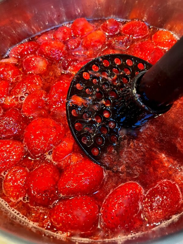 strawberries being mashed in a pot